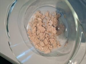 Gedroogde stukjes desemstarter in lauw water om weer actief te maken